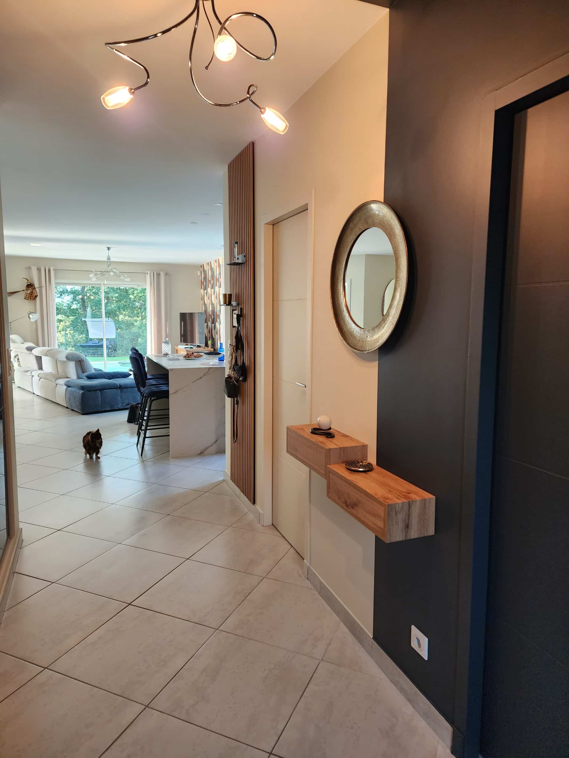 Entrée moderne avec miroir doré, étagères flottantes en bois et vue sur un salon spacieux et lumineux.
