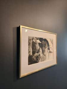 Portrait noir et blanc de Salvador Dalí encadré sur un mur gris foncé.