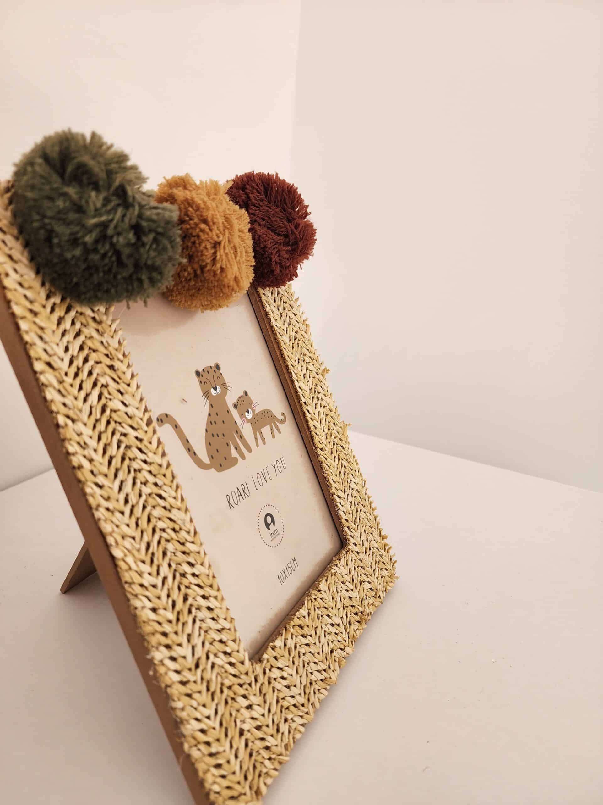 Cadre photo 10x15cm en raphia tressé avec trois pompons (vert, ocre, marron). Illustration de guépards mère et petit: "ROAR! LOVE YOU".