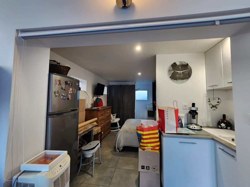 Studio fonctionnel avec kitchenette, lit, frigo décoré et sac de courses Auchan.