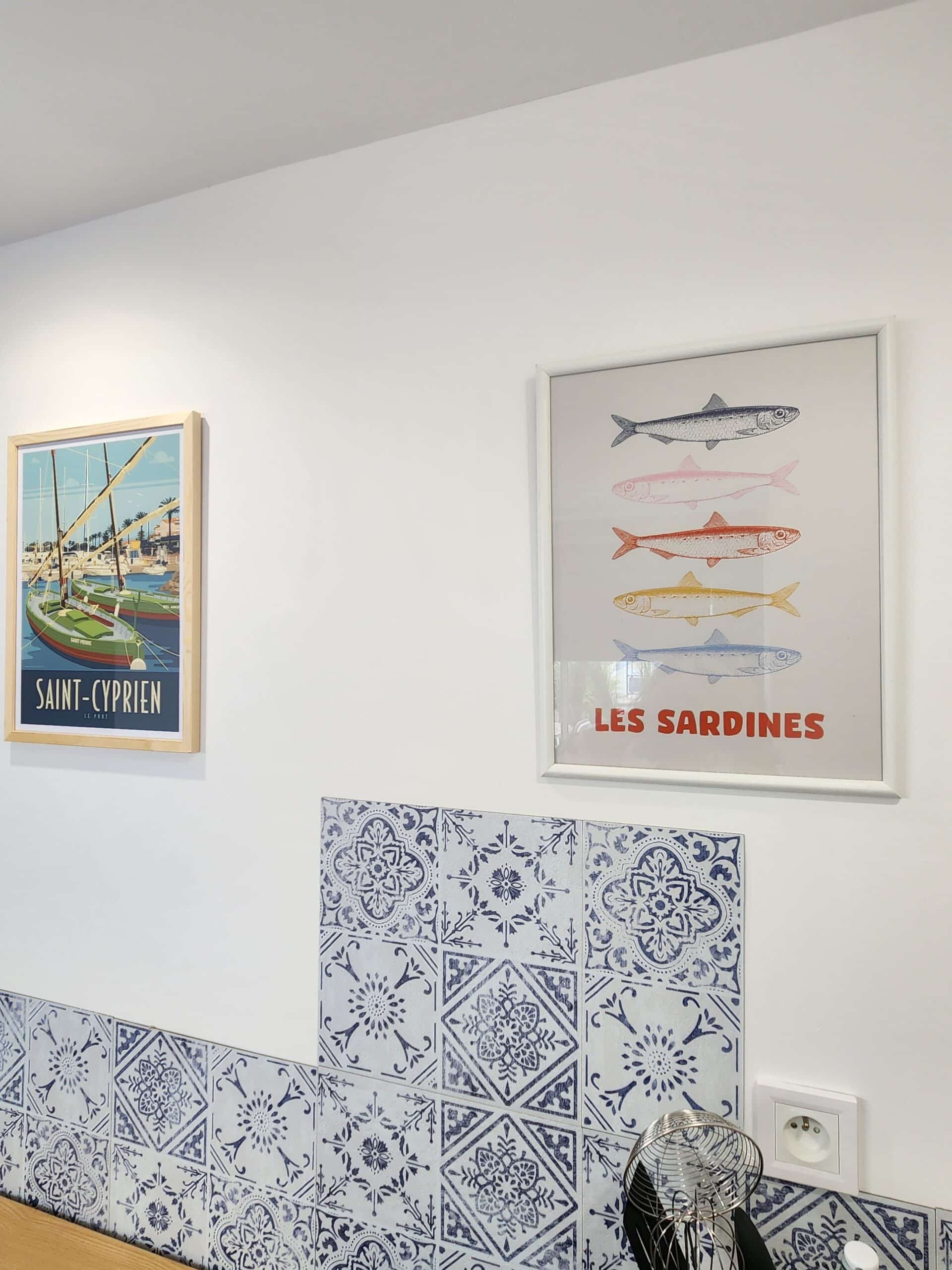 Posters Saint-Cyprien et Les Sardines sur mur blanc avec carreaux de ciment azulejos.