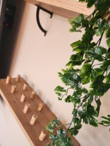 Étagère en bois décorée de bouchons de liège et feuillage artificiel vert.